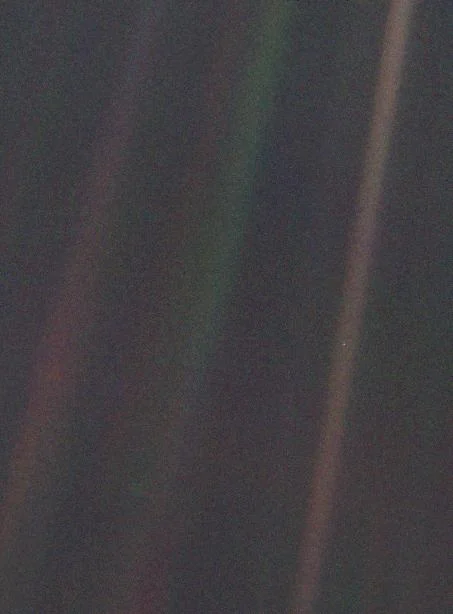 A dark frame crossed by bands of scattered sunlight. Earth is a single faint blue-white dot inside one band.